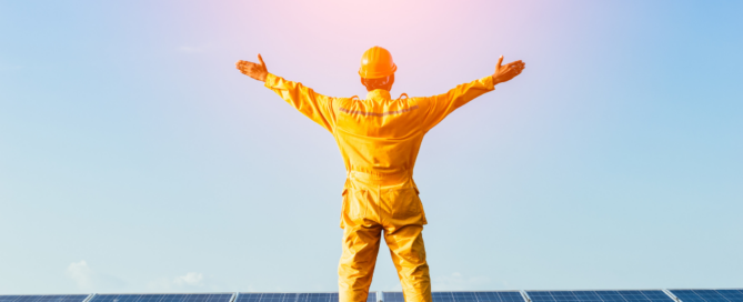 Man Standing On Solar Panels With Arms Spread Out